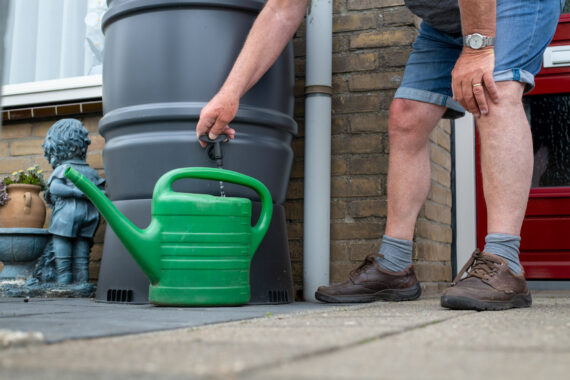 man doet water in gieter vanuit regenton