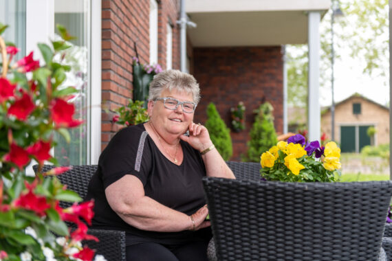 vrouw op terras tussen de bloemen