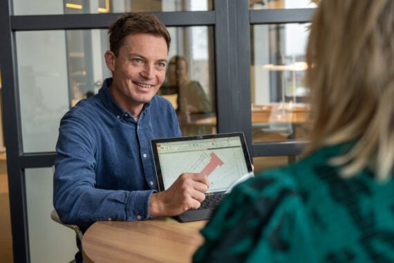 medewerkers in overleg met bouwtekening op laptop